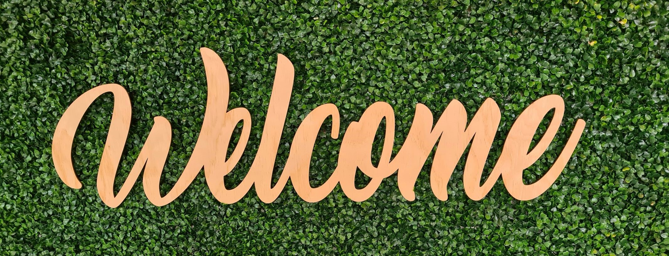 Welcome written with a greenery backdrop